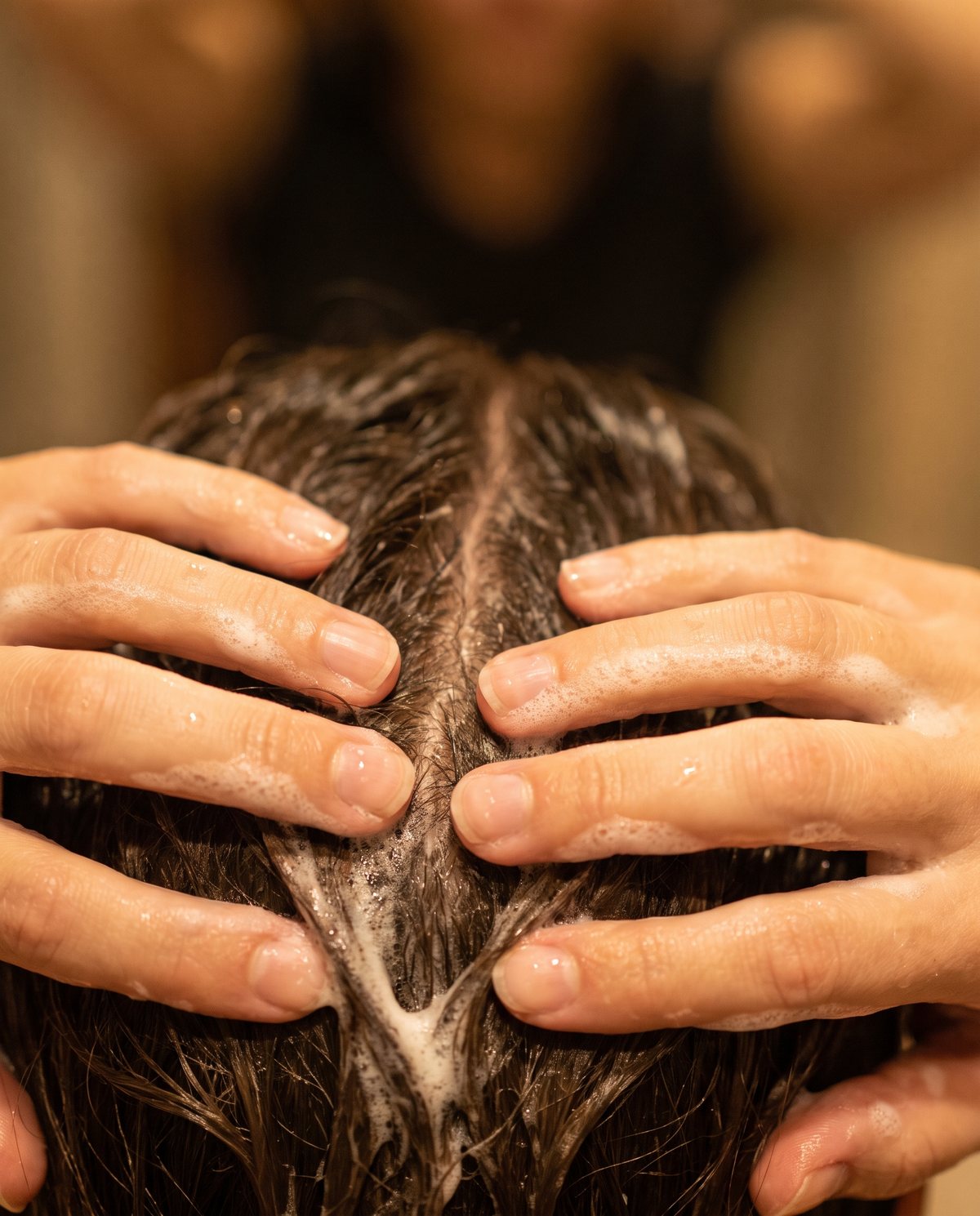 Hands working shampoo lather into the scalp
